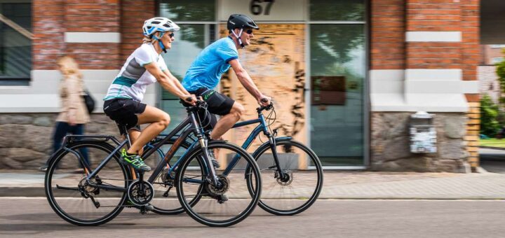 Ein Pärchen fährt auf E-Bikes durch die Stadt.