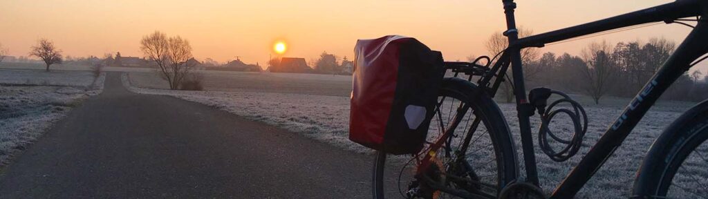 Ein Fahrrad mit einer Hinterradtasche von Ortlieb bei aufgehender Sonne im Winter Ein Fahrrad mit einer Hinterradtasche von Ortlieb bei aufgehender Sonne im Winter