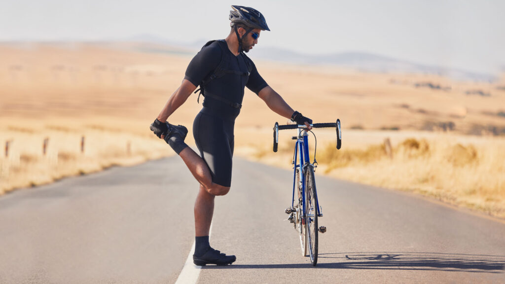 Radfahrer Training - Fahrradfahrer dehnt sich an seinem Fahrrad Radfahrer Training - Fahrradfahrer dehnt sich an seinem Fahrrad