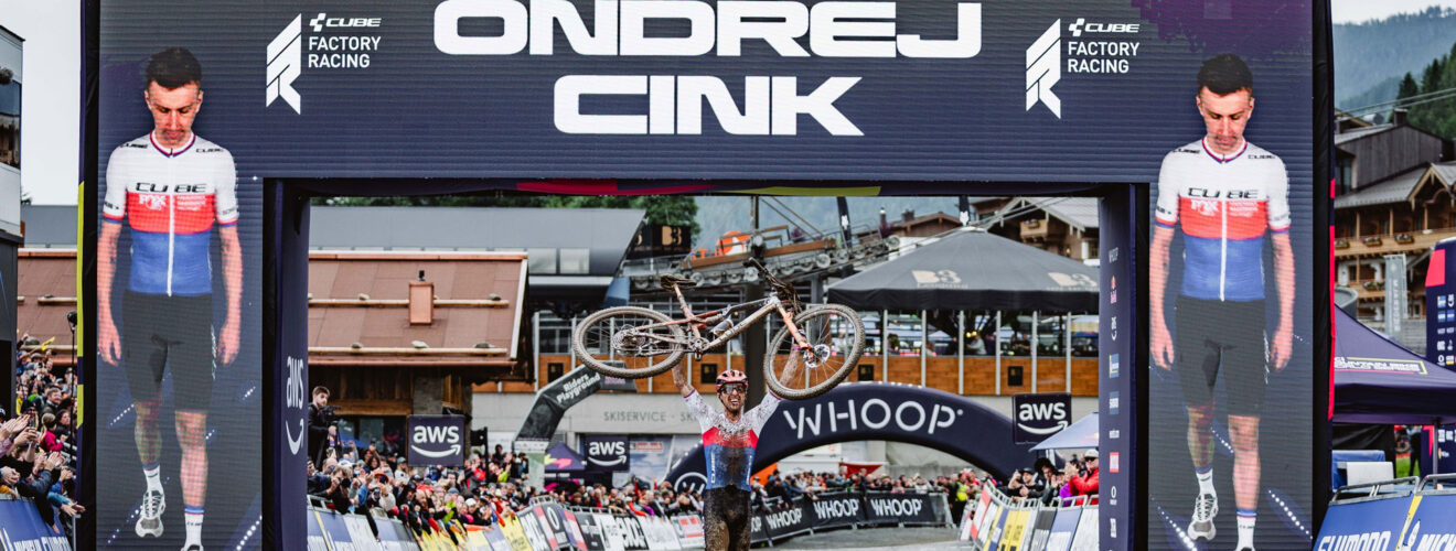 Ondřej Cink jubelt mit hochgehobenem Mountainbike im Ziel des UCI MTB World Cups in Leogang 2025 nach seinem ersten Elite-Weltcupsieg