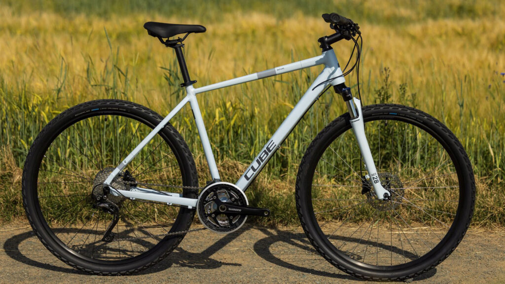 Cube Nature Crossbike on a field path - sporty bike in front of a green-yellow meadow background
