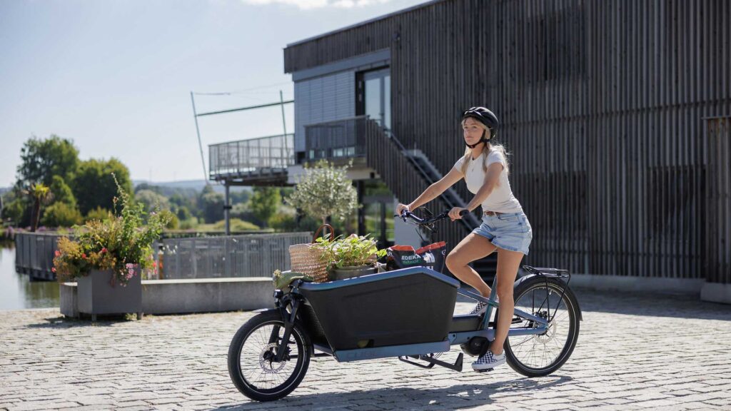 Frau transportiert Pflanze und Erde auf einem Cube 2026 Transport E-Bike Lastenrad.