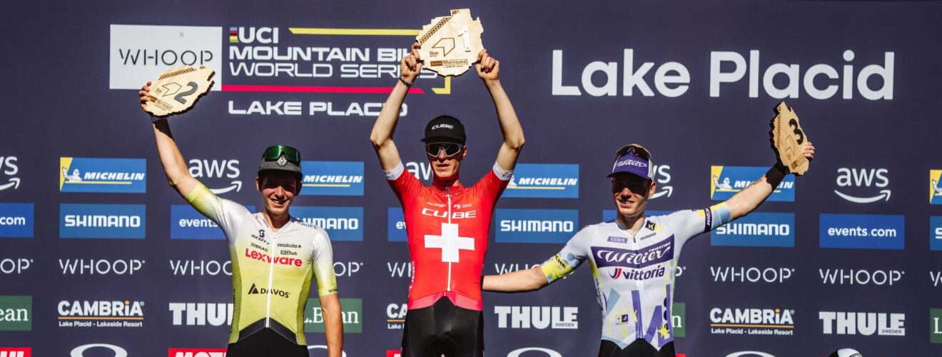 Finn Treudler jubelt auf dem Podium und hält stolz die Trophäe für seinen U23-Triumph in Lake Placid in die Höhe.